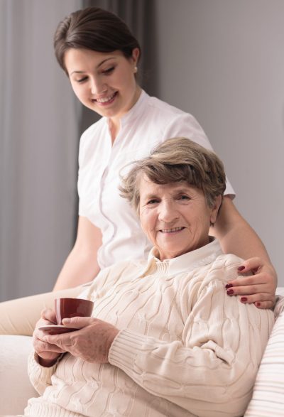 Young female caregiver taking care of older woman